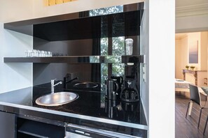 Eine moderne Küche mit schwarzem Arbeitsplatz, Spüle aus Edelstahl und Kaffeemaschine.