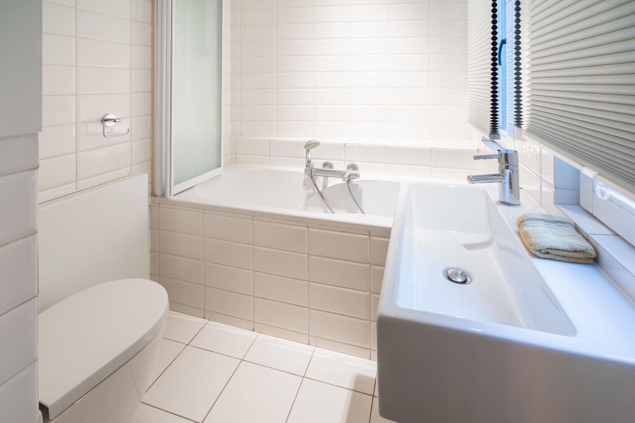 Een moderne badkamer met een badkuip, toilet en wastafel.