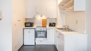 A compact kitchen with white cabinetry, a microwave, a coffee maker, a dishwasher, and a sink. - Antwerp bright apartment stay (Antwerp)