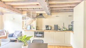 Una cocina compacta con techo de madera, armarios blancos y un comedor con mesa y sillas.