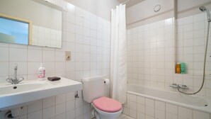 Et badeværelse med hvid vask, toilet og badekar.