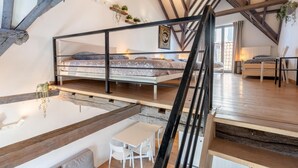 Une chambre de style loft avec un lit superposé, un coin repas avec une table et des chaises, et une petite kitchenette.