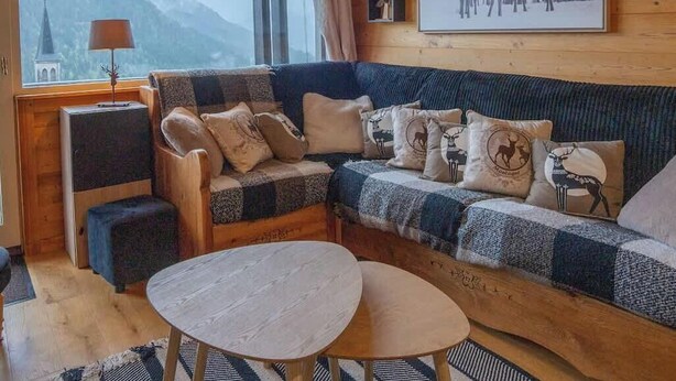 A cozy living room with a wooden sofa, a round table, and a view of a mountain. - Chez Jerome I T3 I Châtel (Châtel)