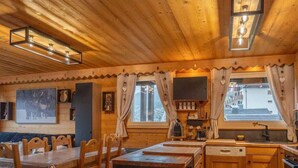 A wooden cabin interior with a dining area, kitchen, and a large window. - Chez Jerome I T3 I Châtel (Châtel)