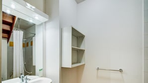 A bathroom with a white sink, mirror, and shower area. - Duplex Apartment in the Heart of Luchon (Bagneres-de-Luchon)