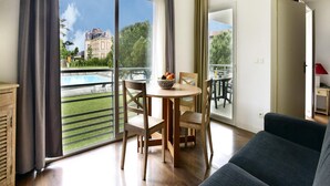 A modern living room with a balcony, a dining table with chairs, and a sofa. - Spacious Stay for 6 in La Rochelle (Lagord)