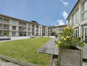 A multi-story hotel with a courtyard, outdoor seating, and a flower planter. - Spacious Stay for 6 in La Rochelle (Lagord)