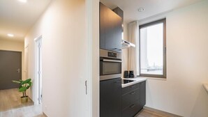 Een moderne keuken met een inbouwoven, magnetron en een raam met uitzicht op de stad.