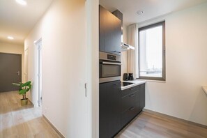 A modern kitchen with a built-in oven, microwave, and a window with a city view. - Aesthetic 12 Guests Apartment with Balcony (Antwerp)