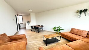 A modern living room with a sofa, coffee table, and dining area. - Spacious City Retreat with Balcony (Antwerp)