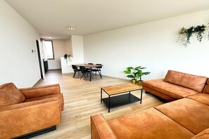 A modern living room with a sofa, coffee table, and dining area. - Spacious City Retreat with Balcony (Antwerp)