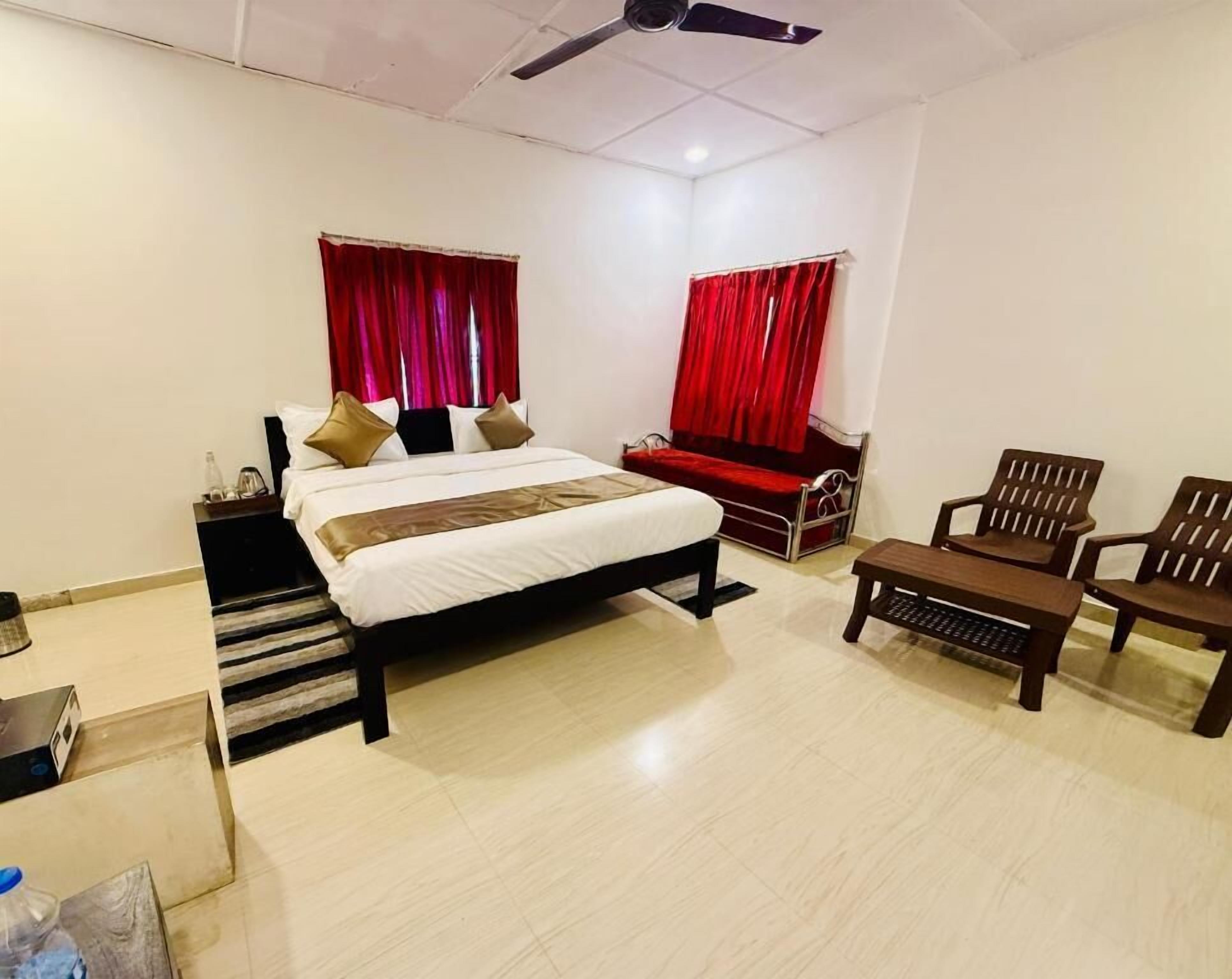 A hotel room with a bed, two chairs, a small table, and a ceiling fan.