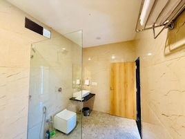 Un baño moderno con cabina de ducha de vidrio, lavamanos blanco y puerta de madera.