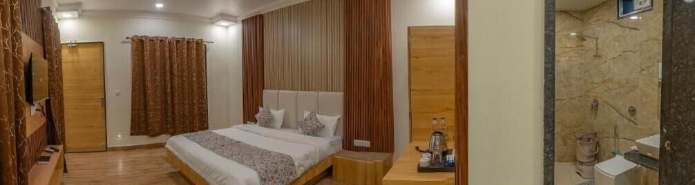 Ein Schlafzimmer mit Bett, Vorhängen, Nachttisch und einem Badezimmer mit Waschbecken und Spiegel.