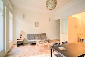 A living room with a sofa, a coffee table, a dining table, and a lamp. - 2-bedroom apartment in Antwerp Centre (Antwerp)