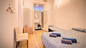A bedroom with a bed, a chair, a radiator, a small table, and a door leading to a bathroom. - 2-bedroom apartment in Antwerp Centre (Antwerp)