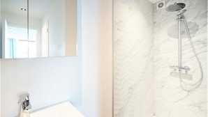 A bathroom with a white sink, a mirror, and a shower with a marble wall. - Saint Pauls 14-persons apartment (Antwerp)