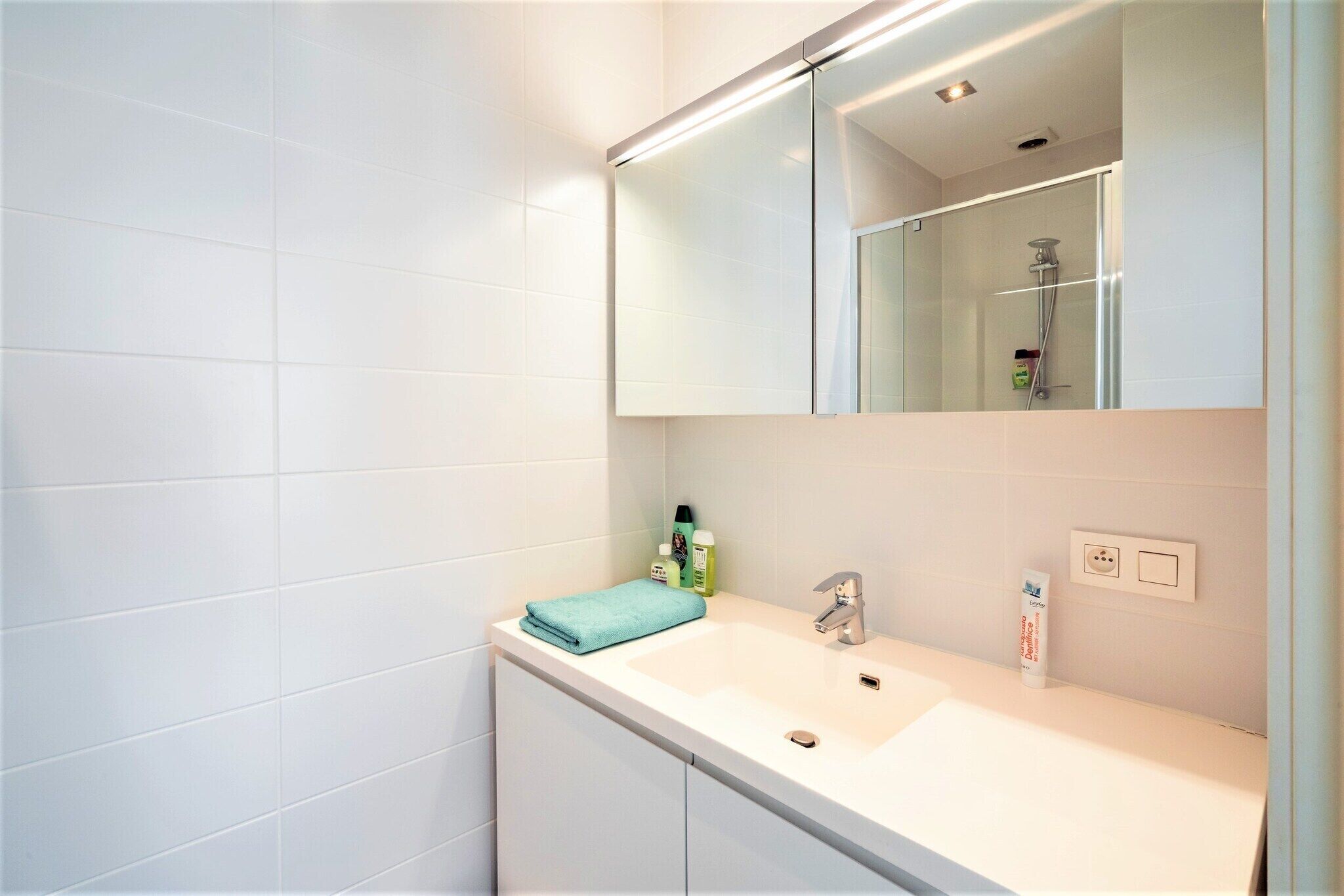 Une salle de bain avec un lavabo blanc, un miroir et une serviette.
