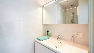 Une salle de bain avec un lavabo blanc, un miroir et une serviette.