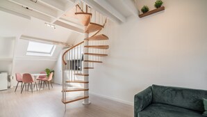 A modern interior with a spiral staircase, a dining area, and a green sofa. - Cosy 1-bedroom apartment, Antwerp (Antwerp)
