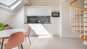 A modern kitchen with white cabinets, a black countertop, and a wooden staircase. - Cosy 1-bedroom apartment, Antwerp (Antwerp)