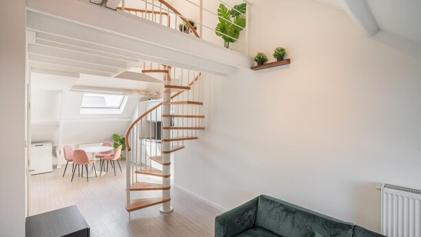 A modern interior with a spiral staircase, a dining area, and a green sofa. - Cosy 1-bedroom apartment, Antwerp (Antwerp)