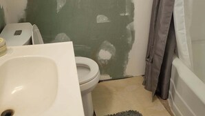 Ett badrum med toalett, handfat och en vägg som är delvis målad.