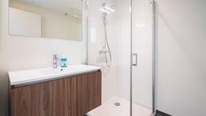 A modern bathroom with a shower, a sink with a mirror, and a wooden vanity. - Urban Family City Escape in Antwerp (Antwerp)