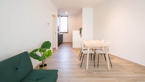A modern living room with a green sofa, a dining table with chairs, and a potted plant. - Urban Family City Escape in Antwerp (Antwerp)