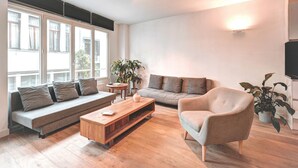Una sala de estar moderna con un sofá, un sillón, una mesa de centro y plantas en macetas.