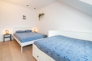 A bedroom with two beds, a bedside table with a lamp, a wall-mounted plant, and a small picture. - 2-bedroom apartment in Central location (Antwerp Center)