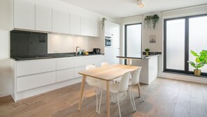 Una cocina moderna con armarios blancos, encimera negra y mesa de comedor de madera con sillas.