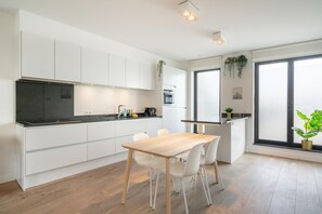 Eine moderne Küche mit weißen Schränken, einer schwarzen Arbeitsplatte und einem Holzespeisesaal mit Stühlen.