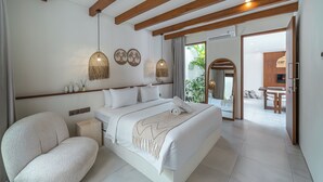 Una habitación de hotel moderna con una cama grande, un espacio para sentarse, vigas de madera, un televisor y un comedor.
