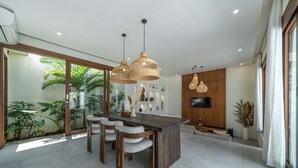 Una cocina moderna con una isla central, luces colgantes y un televisor montado en la pared.