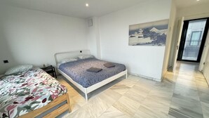 Une chambre à coucher comprenant un lit, une table de chevet, une étagère fixée au mur et un tableau.