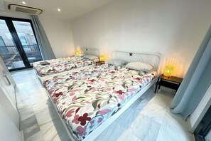Een hotelkamer met twee bedden, een klein tafeltje, een lamp en uitzicht door een schuifdeur.