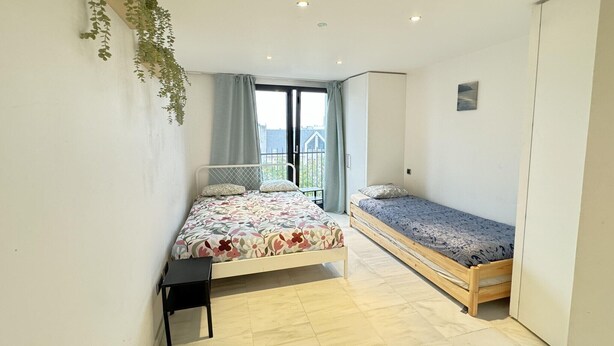 Une chambre avec un lit, une petite table, un canapé-lit et un balcon.