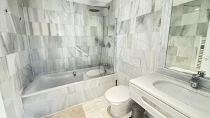 Une salle de bain moderne avec une douche à parois de verre, une baignoire, des toilettes et un lavabo avec un miroir.