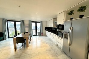 Una cocina moderna con comedor, ventanas amplias y vista a edificios.