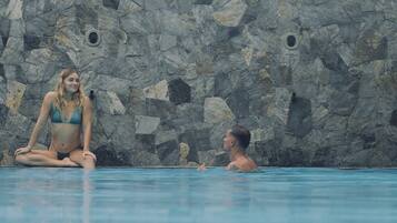 Una piscina con un muro de piedra de fondo.