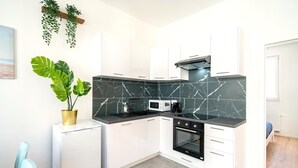 A compact kitchen with white cabinets, a black marble backsplash, a built-in oven, and a microwave.