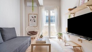 A living room with a sofa, a coffee table, a TV, a hanging chair, and a balcony with a view. - STM Monastiraki Acropolis Apt (Athina)