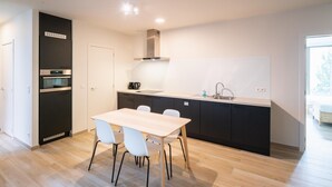Una cucina moderna con tavolo da pranzo, sedie ed elettrodomestici integrati.