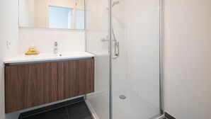 Ein Badezimmer mit Glasdusche, Holzwaschtisch und Spiegel über dem Waschbecken.