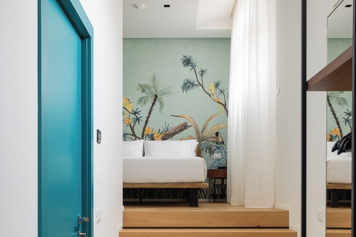 Ein modernes Schlafzimmer mit einem Bett, einem Nachttisch, einem Spiegel und einer Treppe, die in einen anderen Raum führt.