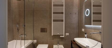 Un baño moderno con bañera, inodoro, bidé y tocador con lavamanos.