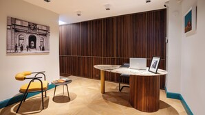 A modern interior with a round wooden table, a yellow chair, and a wall-mounted picture. - Atelier Alinari Rooms (Florence)