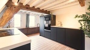Eine moderne Küche mit Holzbalkendecke, integrierten Geräten und einem großen Fenster.