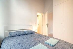 Ein Schlafzimmer mit einem Bett, Kissen, einem gefalteten Handtuch und einem Kleiderschrank.